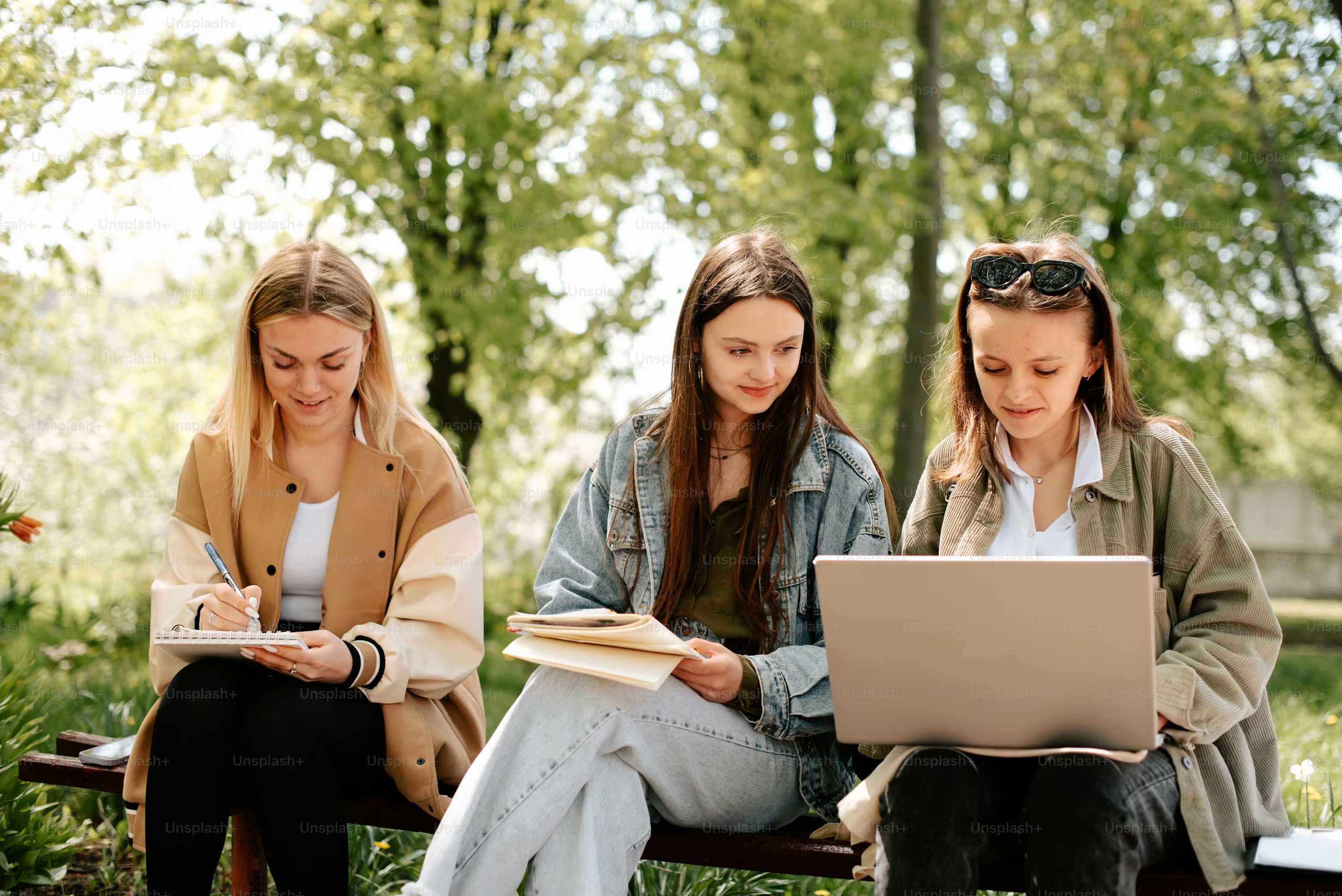 Three YSP fellows collaborating outdoors — one taking notes, one with a notebook, one on a laptop.
